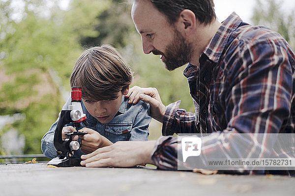 Vater und Sohn betrachten Objekte unter dem Mikroskop