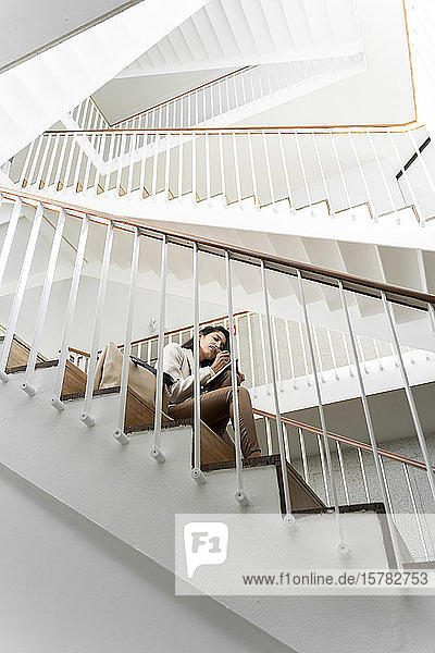 Young woman sitting on stairs taking notes