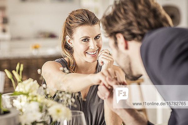 Lächelnde junge Frau sieht ihren Freund an  der ihre Hand küsst