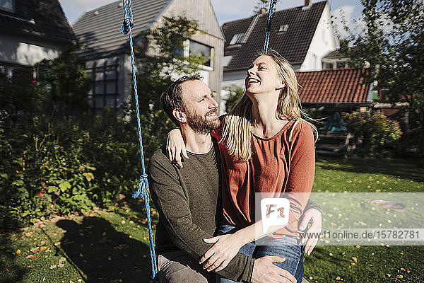 Affectionate couple sitting on swing in in their garden