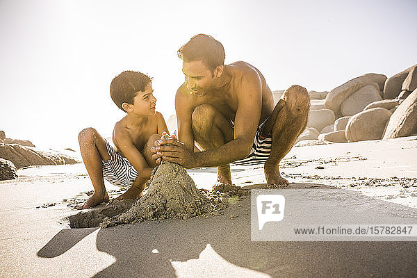 Vater und Sohn bauen gemeinsam eine Sandburg am Strand