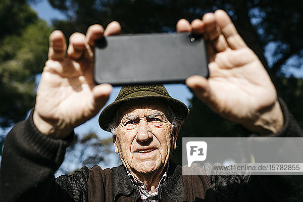 Old man taking pictutes with his smartphone