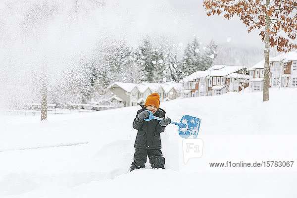 Lachender kleiner Junge schaufelt Schnee  Vancouver  Kanada