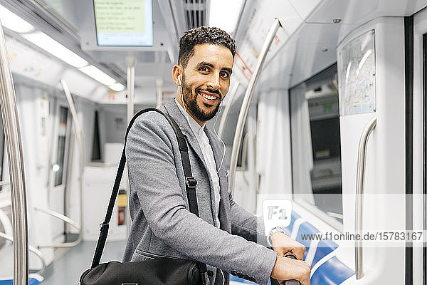 Portrait of smiling young businessman with earphones on the subway