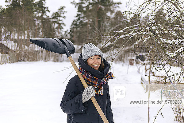 Portrait of smiling woman with snow shovel
