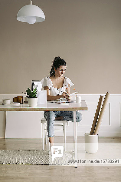 Junge Frau sitzt zu Hause am Tisch