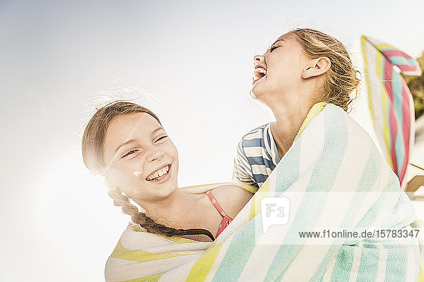 Two laughing cute girls wrapped in a towel