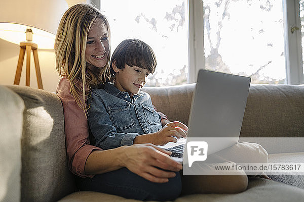 Mutter und Sohn sitzen auf dem Sofa und benutzen einen Laptop