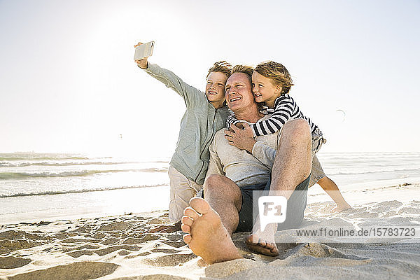 Junge mit Bruder und Vater beim Selbermachen am Strand