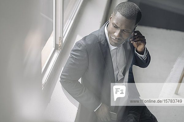 Portrait of pensive young businessman leaning on window sill in office