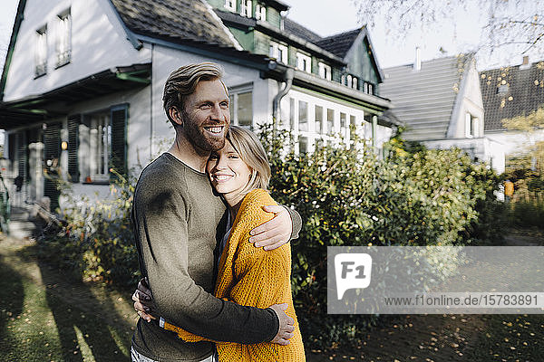 Glückliches Paar umarmt sich vor ihrem Haus