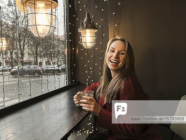 Porträt einer lachenden jungen Frau mit einer Tasse Tee in einem Café