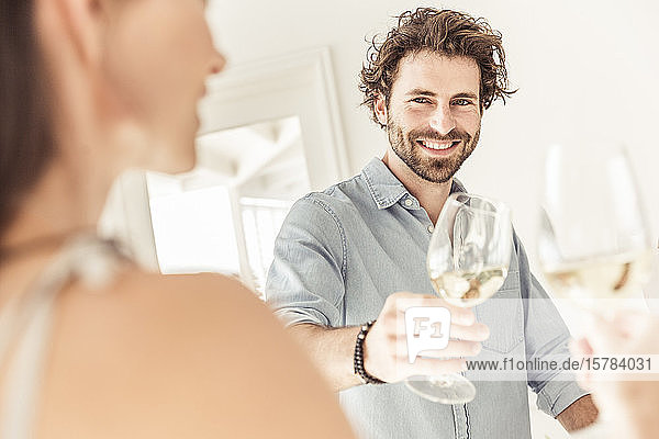 Porträt eines lächelnden Mannes mit einem Glas Weißwein