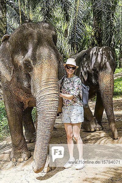 Porträt einer lächelnden Frau mit Elefanten in einem Schutzgebiet  Krabi  Thailand