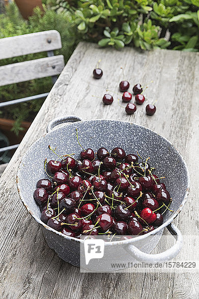 Cherries in enamel vintage bowl on garden table