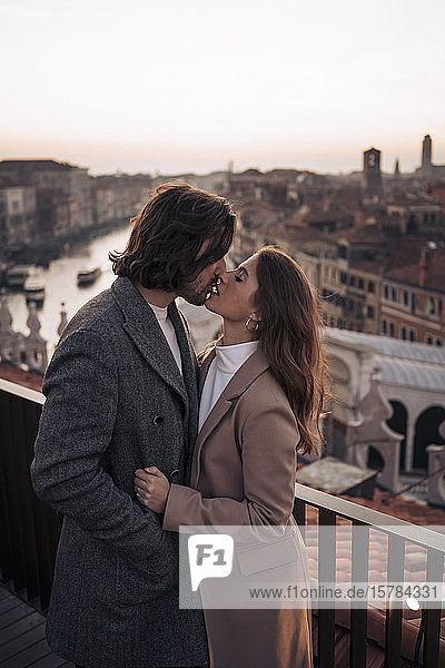 Zärtliches junges Paar küsst sich auf einem Balkon über der Stadt Venedig  Italien