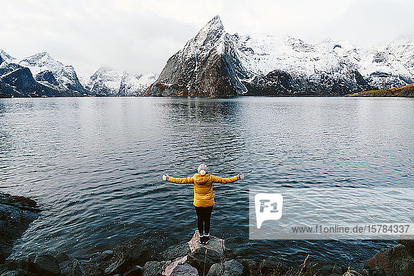 Tourist steht auf einem Felsen und genießt die Aussicht auf Hamnoy  Lofoten  Norwegen