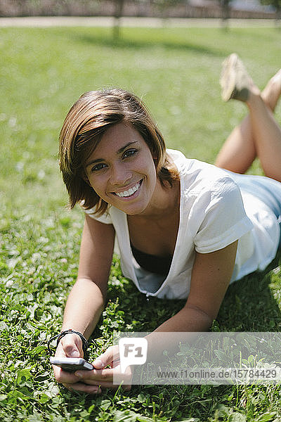 Portrait of smiling young woman with cell phone on a meadow