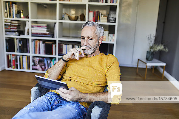 Relaxed mature man at home using tablet