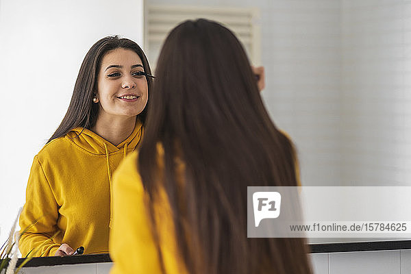 Spiegelbild eines Teenager-Mädchens beim Auftragen von Wimperntusche