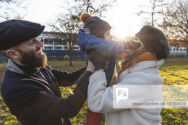 Happy affectionate couple with baby son at park