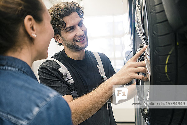 Lächelnder Automechaniker und Kunde betrachtet Reifen in der Werkstatt