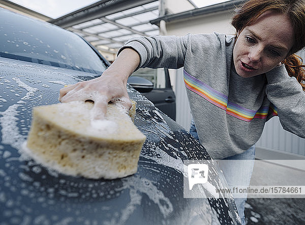 Rothaarige Frau reinigt ihr Auto