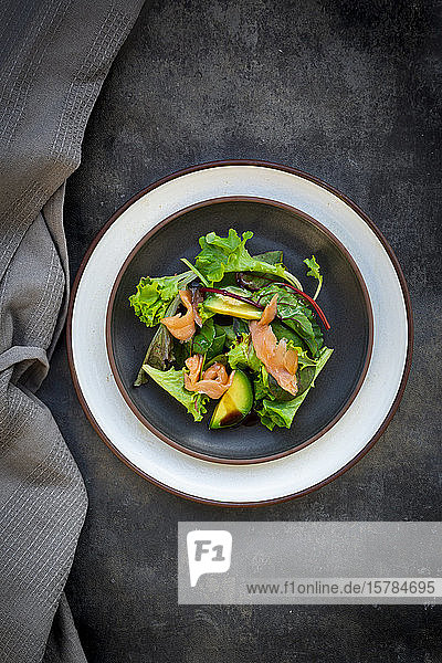 Teller grüner Salat mit Feldsalat Rucola Spinat rotem Blattsalat Rote-Bete-Blättern Avocado Lachsfleisch und Balsamico-Essig
