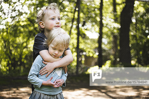 Boy hugging his little sister outdoors