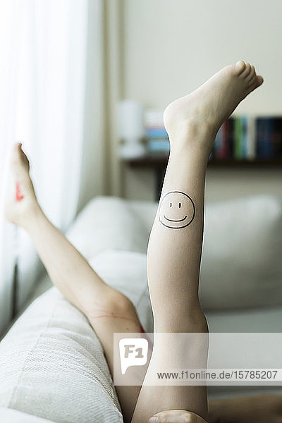 Mädchenbein mit gemaltem Smiley-Gesicht
