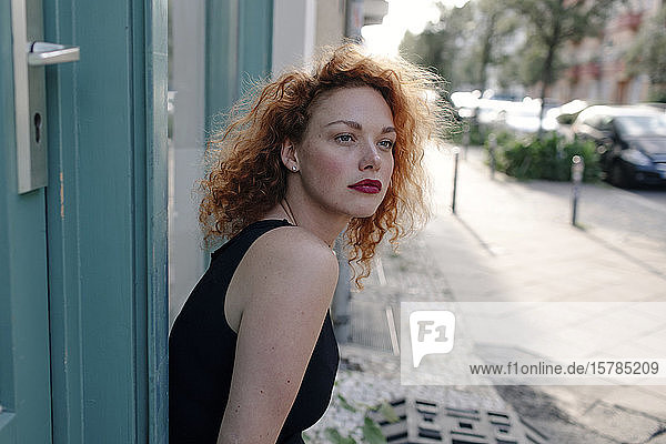 Porträt einer rothaarigen Frau vor einem Café mit Blick zur Seite