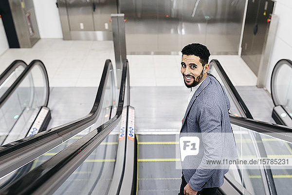 Porträt eines lächelnden jungen Geschäftsmannes auf einer sich umdrehenden Rolltreppe