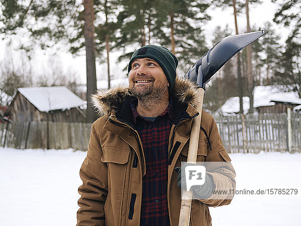 Portrait of smiling man with snow shovel looking up