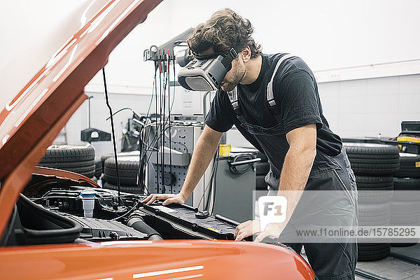 Automechaniker mit VR-Brille in einer Werkstatt bei der Arbeit am Auto