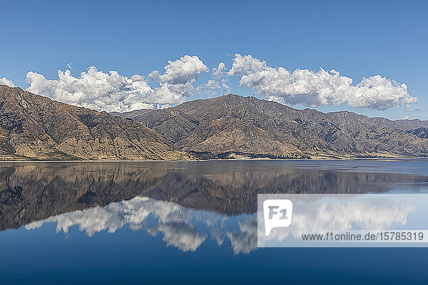 Neuseeland  Queenstown-Lakes District  Wanaka  Hügel und blauer Sommerhimmel  der sich im Hawea-See spiegelt