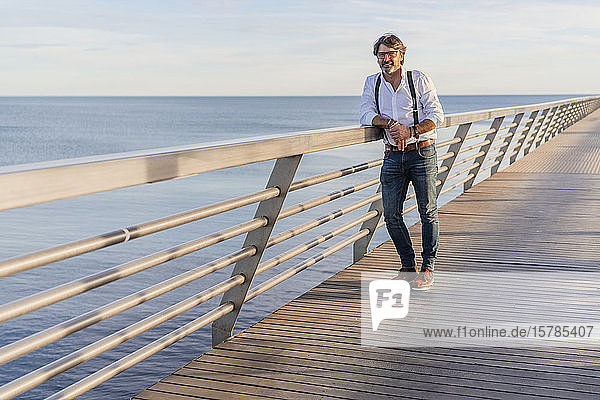 Man leaning on railing on a jetty