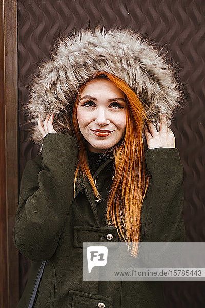 Porträt einer lächelnden rothaarigen jungen Frau mit Kapuzenjacke