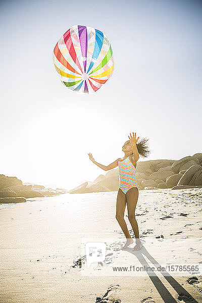 Glückliches Mädchen spielt mit aufblasbarem Ball am Strand