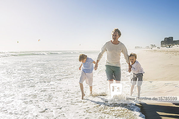 Father walking on the beach with his sons