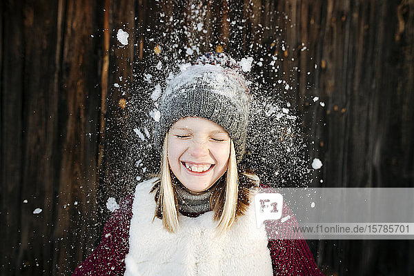 Schnee fällt auf glückliches Mädchen mit Wollmütze