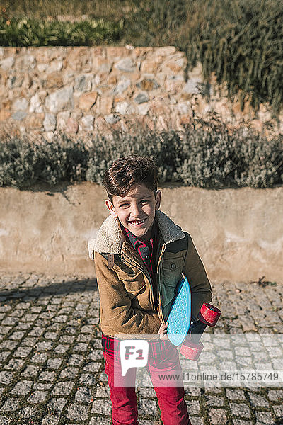 Portrait of happy boy holding skateboard