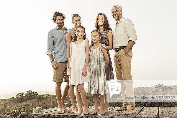 Große Familie genießt den Sonnenuntergang stehend an einer Strandpromenade