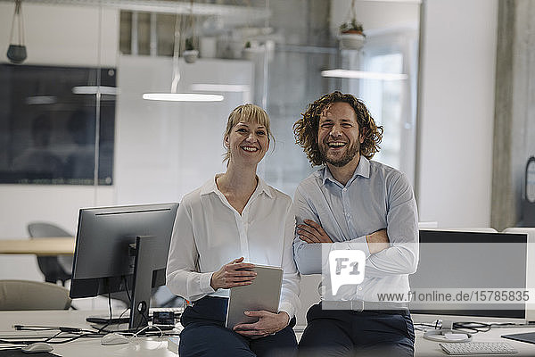 Porträt eines glücklichen Geschäftsmannes und einer Geschäftsfrau mit Tablette im Büro