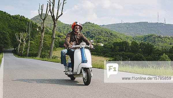 Ehepaar fährt Oldtimer-Motorroller auf der Landstraße  Toskana  Italien