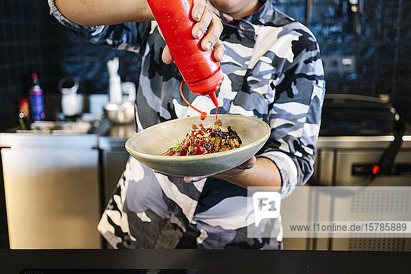 Koch der ein Gericht in der Restaurantküche zubereitet