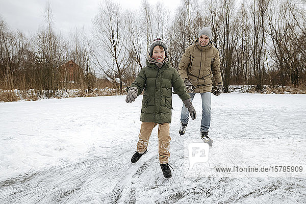Happy boy skating together with father on ice