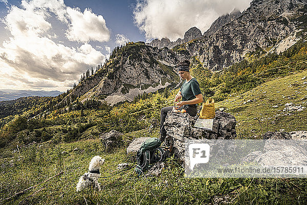 Woman with dog on a hiking trip at Wilder Kaiser having a break  Kaiser mountains  Tyrol  Austria