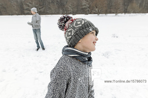 Portait of smiling boy in winter landscape with father in background