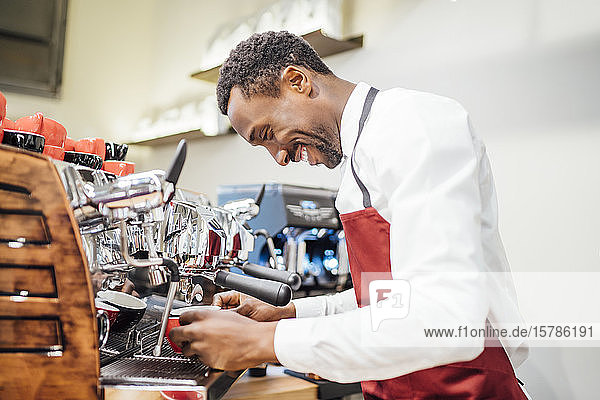 Smiling barista preparing a coffee in a coffee shop