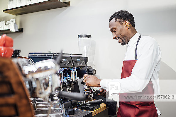 Lächelnder Barista bei der Zubereitung eines Kaffees in einem Café